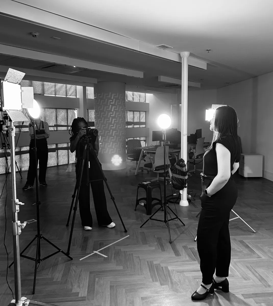 Bastidores de um set de fotografia com Isis, entre luzes e tripés, em preto e branco